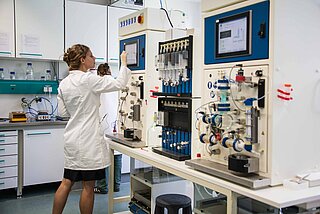 Eine Wissenschaftlerin mit Kittel in einem technischen Labor