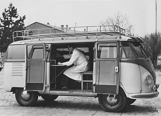 Seitliches schwarz-weiß Foto eines VW-Busses mit Laborgeräten und einem Wissenschaftler darin