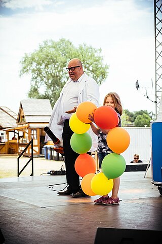 Ein Wissenschaftler auf einer Bühne mit Luftballons